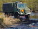 1995 Dodge 1500 - This military truck navigates a wet, off-road environment with tall grass and trees in the background.