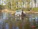 1995 Dodge 1500 - A Suzuki Samurai navigates a challenging muddy water obstacle, kicking up a large spray.