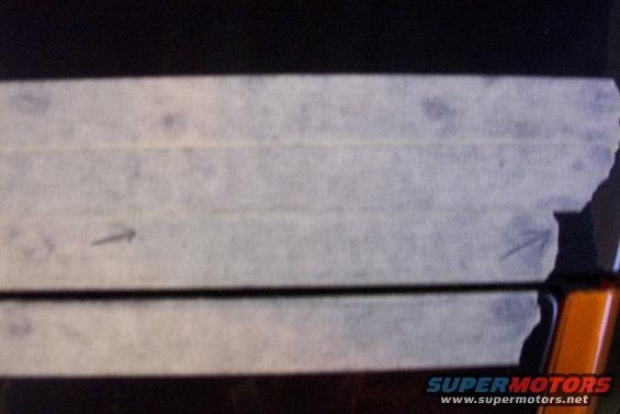 Masking tape applied to a dark car part with faint markings