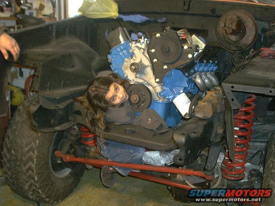 Child lying on engine and suspension components in a workshop