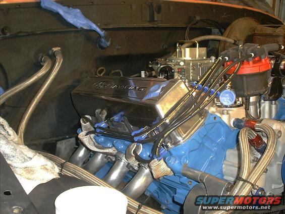 Engine with blue block, chrome valve covers reading "Ford Racing", and a carburetor
