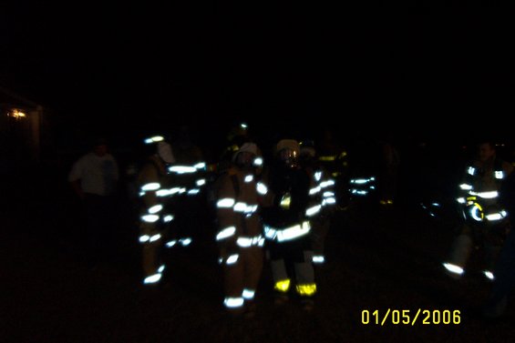 Firefighters in reflective gear at night with date 01/05/2006 visible