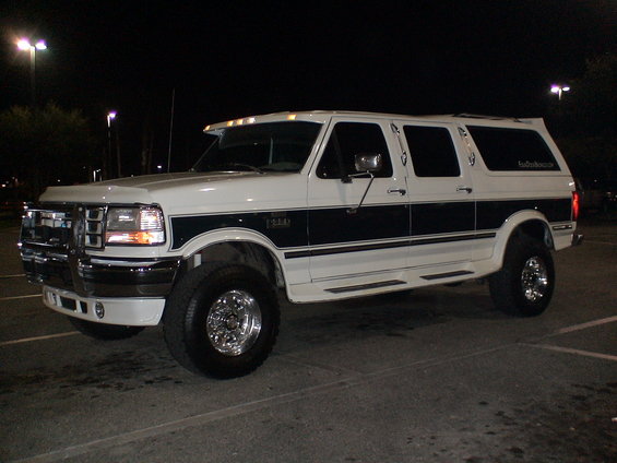 White Ford SUV with dark side trim and chrome wheels, parked at night