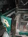 1983 Ford Bronco - A detached green vehicle fender with a yellow ribbon decal is shown in a workshop setting.
