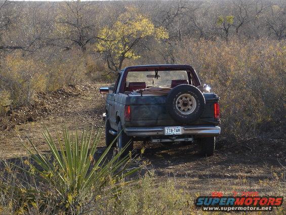 Ford Bronco parked on a dirt road in a dry, brushy area. Spare tire mounted on the back