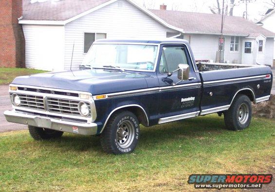 Dark blue 1975 Ford F-150 pickup truck with chrome trim and a "Ranger XLT" badge, parked on grass