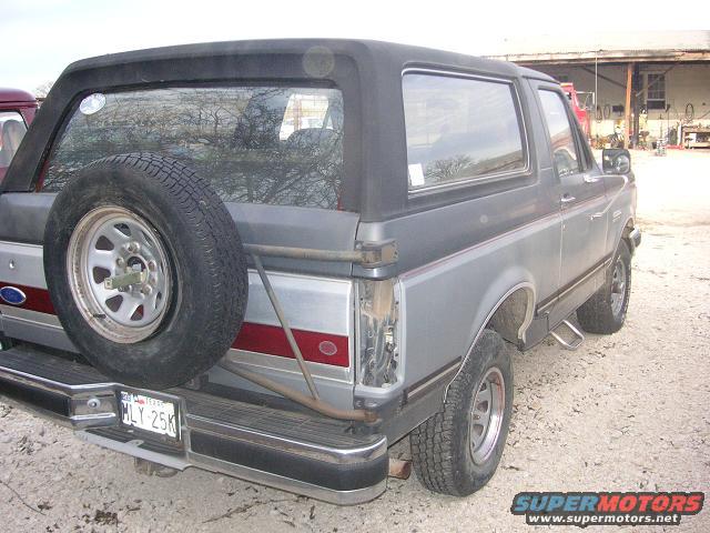 Gray SUV's rear with spare tire, red stripe, and Texas license plate MLY 25K