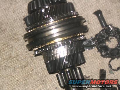 Damaged transmission gears with metal shavings and a broken shaft on a textured surface