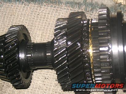 Close-up of transmission gears, some showing wear. Supermotors.net logo visible