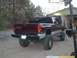 2001 Dodge 1500 - A maroon pickup truck with a lifted suspension and large off-road tires is parked outdoors with its hood up.