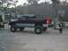 2001 Dodge 1500 - A lifted pickup truck is parked in a yard with a basketball hoop and a dog nearby.