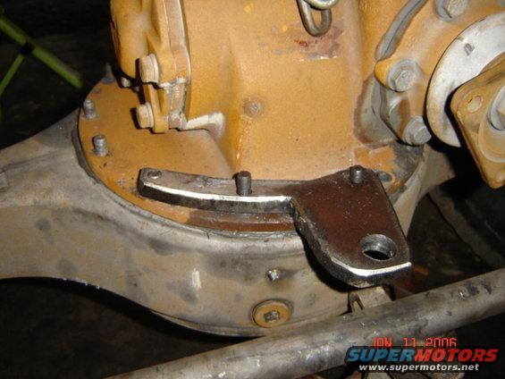 Close-up of a differential housing with a metal bracket attached. Watermark reads 'Supermotors.net'