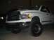 2001 Dodge 1500 - A lifted white Dodge pickup truck is shown from the front-right side, with another vehicle visible to its left.