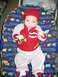 2002 Ford Taurus - A baby is dressed in a red hat and a red and gray jacket with 'Junior Racer' written on it.
