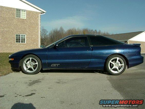 Blue 1995 Ford Probe GT parked on asphalt, side view. Building in background