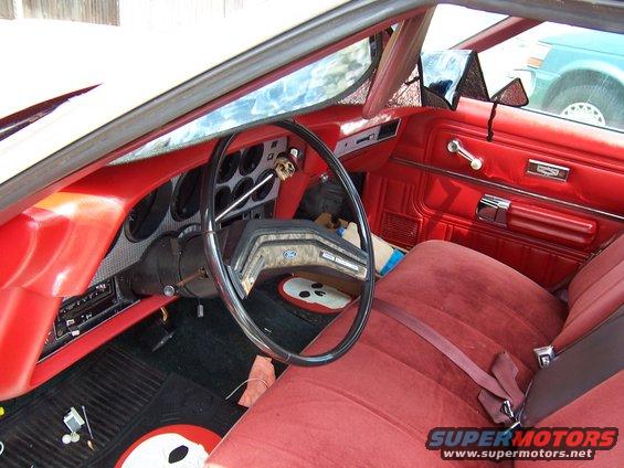 Interior of a 1979 Ford Ranchero with red seats and door panels, and a skull-shaped gear shift knob