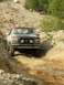 1995 Ford Bronco - A red Ford Bronco navigates a steep, rocky incline on a dirt trail.