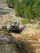 1995 Ford Bronco - A red Ford Bronco navigates a challenging dirt path, demonstrating its off-road capabilities.