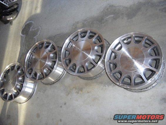 Four aluminum alloy wheels with a 10-spoke design, resting on a concrete surface