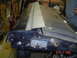 1993 Ford Bronco - Close-up view of a tailgate latch mechanism on a dark blue vehicle part, showing wear and tear.