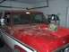 1978 Ford Bronco - A red and white 1978 Ford Bronco is parked in a garage with a camouflage helmet resting on its hood.