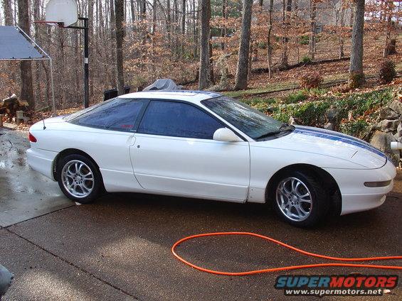 White 1993 Ford Probe coupe with blue racing stripes parked on a driveway
