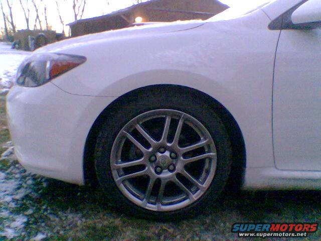 White car's front wheel and fender. It's a 2005 Scion tC