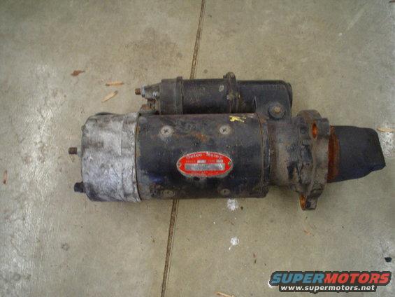 Black starter motor with red oval Delco-Remy label, on concrete