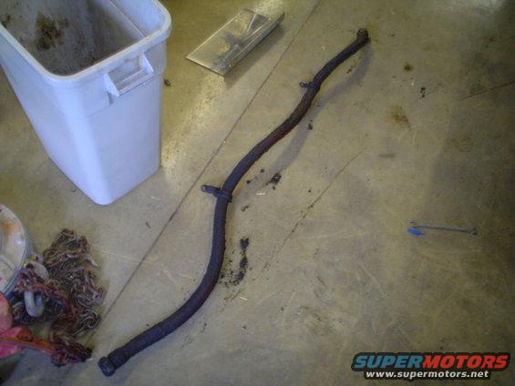 Dark hose on concrete floor near white bin and chains