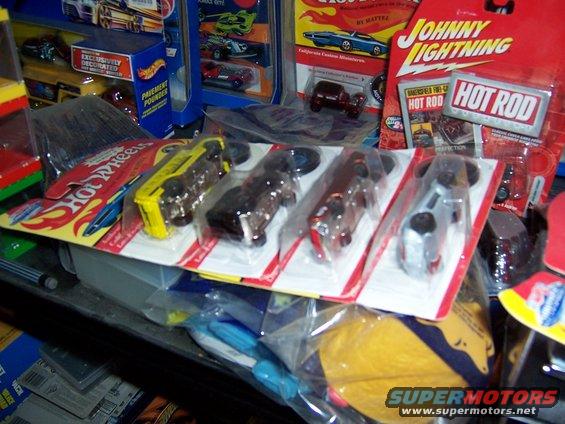 Several Hot Wheels and Johnny Lightning toy cars in packaging on a shelf
