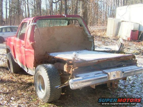 red pickup truck body, rear view, modified bed with wood paneling, snow on bed, another car in background