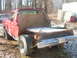 1984 Ford Bronco - This heavily modified red pickup truck sits in a wooded area with snow on the ground.