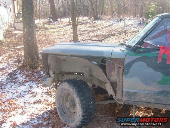 Front fender removed from a 1980s Ford Bronco, showing rust and exposed suspension components