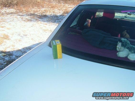 Box on dashboard of car, looking into the back seat with stuff piled up