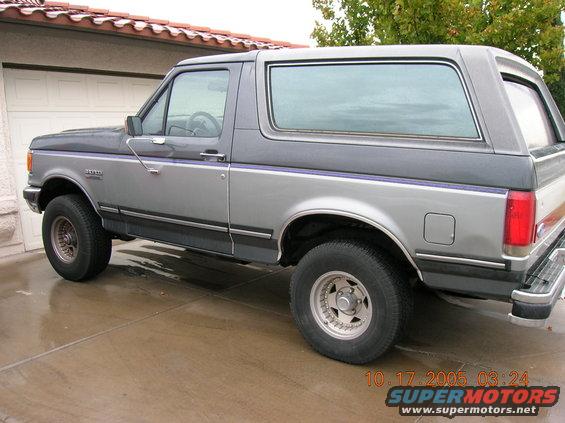 Gray and dark gray Ford Bronco parked in driveway. Side view shows front and rear wheels, doors, and rear quarter panel