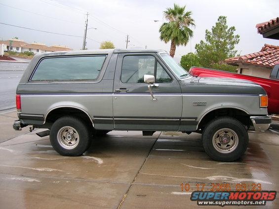 Gray and dark gray two-tone Ford Bronco SUV parked on a wet concrete driveway