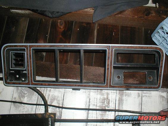 Dashboard trim panel with wood grain accents and air vent