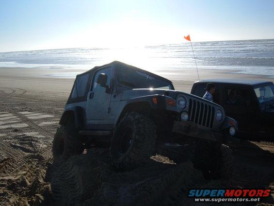 Jeep Wrangler with soft top on a sand dune, another dark SUV behind it
