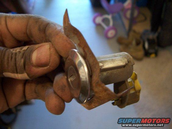 Ignition lock cylinder with keyhole held by a dirty hand with a bandaged thumb