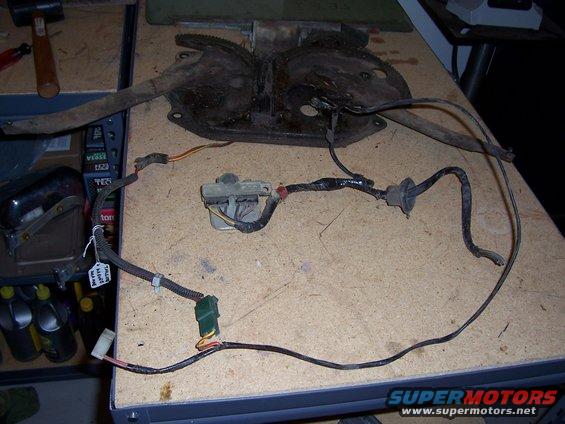 Window regulator mechanism with attached wiring harness laid out on a workbench
