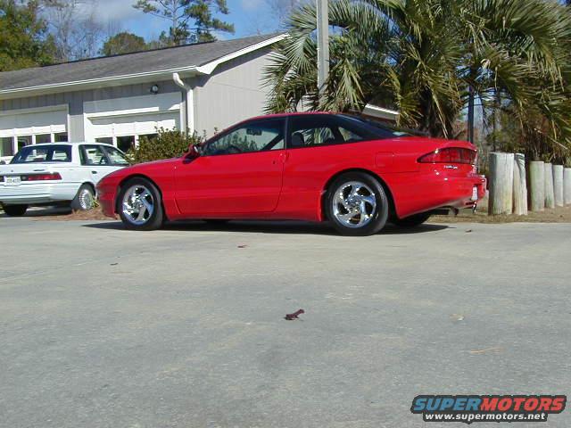 Red 1997 Ford Probe parked next to a white car. The Probe has a black roof and aftermarket wheels