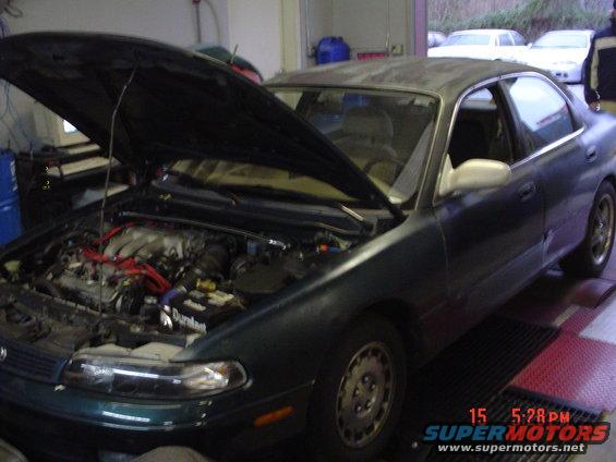 Dark green sedan, hood open, showing engine bay. Visible text 'Durant'