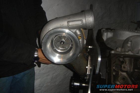 Person holding a turbocharger next to an engine block