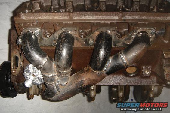 Engine block with custom exhaust headers and a black pulley wheel