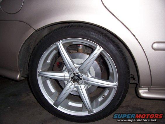 Silver aftermarket wheel on a tan car's rear side