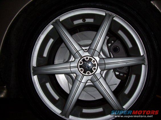 Close-up of a custom alloy wheel with six split spokes and slotted brake rotors