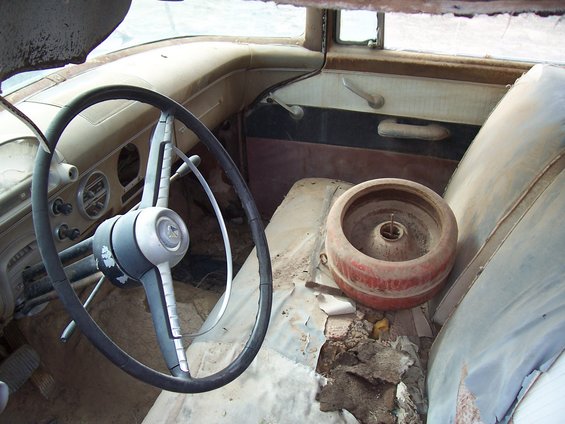 1955 Ford Customline interior with cracked steering wheel and worn seats
