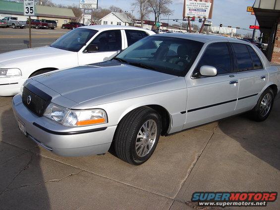 Silver 2000 Ford Crown Victoria parked on concrete, white sedan behind it