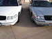 2000 Ford Crown Victoria - A white and a silver 2000 Ford Crown Victoria are parked next to each other, showing their front ends.