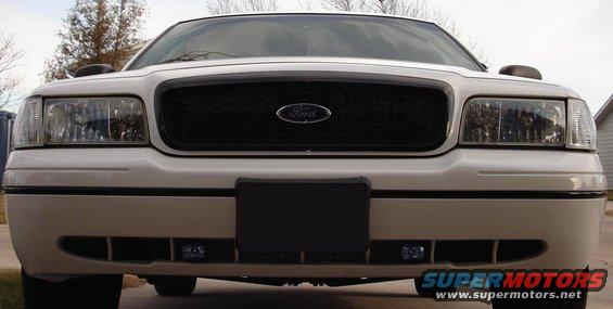 White 2000 Ford Crown Victoria front grille and headlights, license plate area obscured
